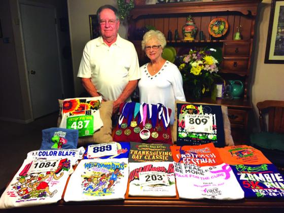 Bob and Carolyn Webb displaying the any medals and t-shirts collected over the years. courtesy photo
